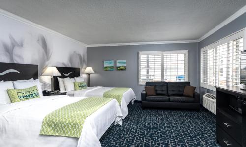 ロサンゼルスにあるDusk Hotel Hollywoodのベッド2台とソファが備わるホテルルームです。