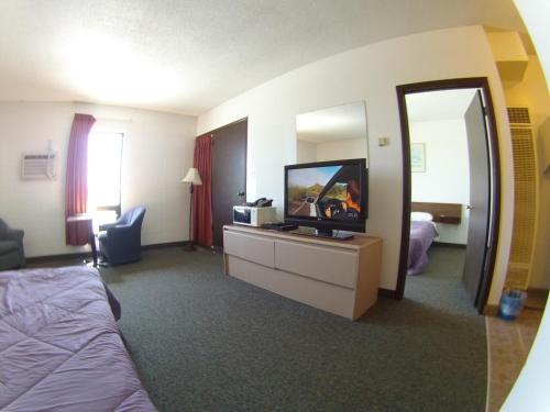 a hotel room with a tv and a bed and a mirror at Rycroft Hotel in Rycroft