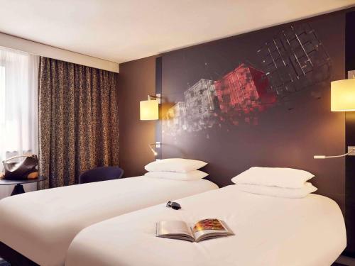 a hotel room with two beds with a book on them at Mercure Le Havre Centre Bassin Du Commerce in Le Havre