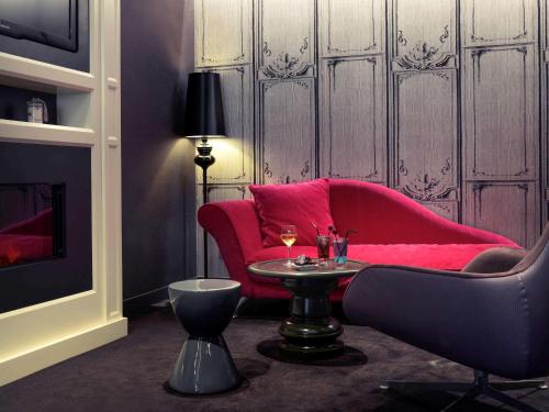 a living room with a red couch and a table at Mercure Toulouse Centre Wilson Capitole in Toulouse