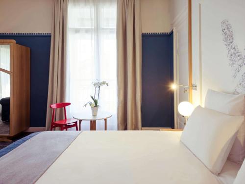 a bedroom with a large white bed and a red chair at Mercure Lyon Centre Château Perrache in Lyon