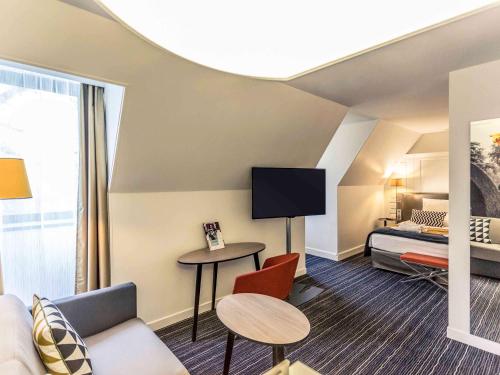 a hotel suite with a bed and a living room at Hotel De Bourbon Grand Hotel Mercure Bourges in Bourges