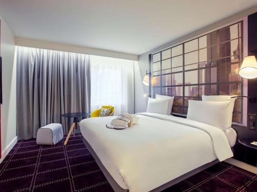 a hotel room with a large white bed and a window at Mercure Paris la Défense Grande Arche in Nanterre
