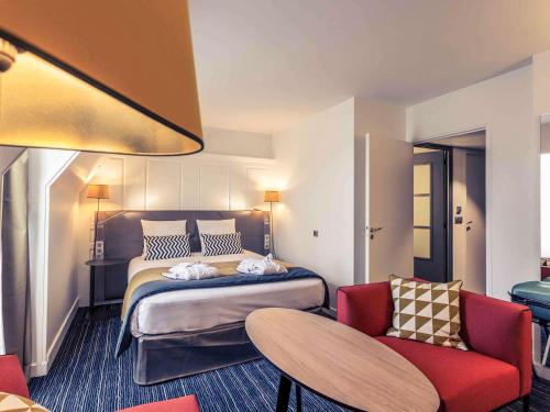 a hotel room with a bed and a red chair at Hotel De Bourbon Grand Hotel Mercure Bourges in Bourges
