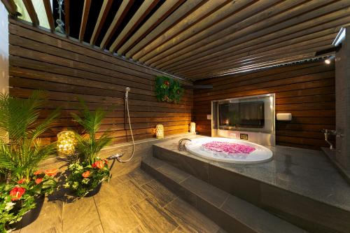 baño con bañera, TV y flores en i RESORT ARTIA Luxury Gifu (Adult Only), en Gifu