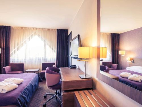 a hotel room with two beds and a desk at Mercure Jelenia Góra in Jelenia Góra