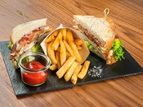 a black plate with a sandwich and french fries at Mercure Gdynia Centrum in Gdynia