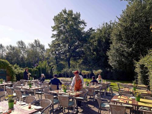a group of people sitting at tables in a garden at Mercure Tagungs- & Landhotel Krefeld in Krefeld
