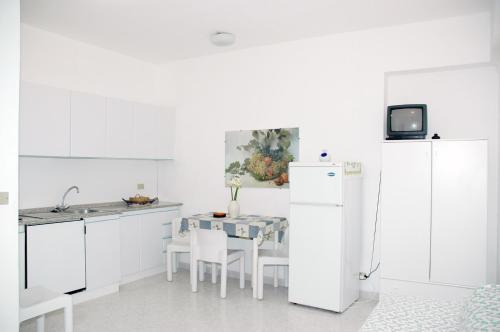 a kitchen with white cabinets and a table and a refrigerator at Villa Oleandro in Capoliveri