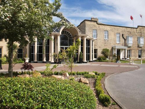 a large brick building with a tree in front of it at Mercure York Fairfield Manor Hotel in York