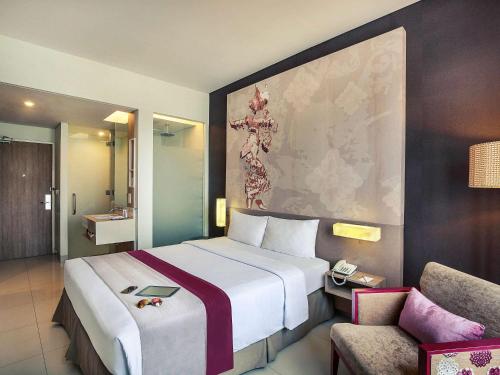 a hotel room with a large bed and a chair at Mercure Bali Nusa Dua in Nusa Dua