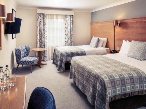 a hotel room with two beds and a table at Mercure Gloucester Bowden Hall Hotel in Gloucester