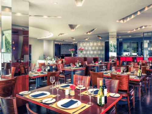 a restaurant with tables and chairs with wine glasses at Mercure Santiago Centro in Santiago
