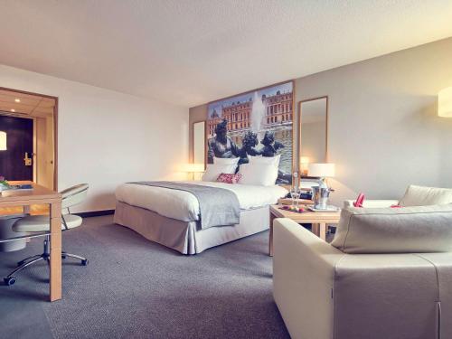 a hotel room with a large bed and a desk at Mercure Paris Velizy in Vélizy-Villacoublay