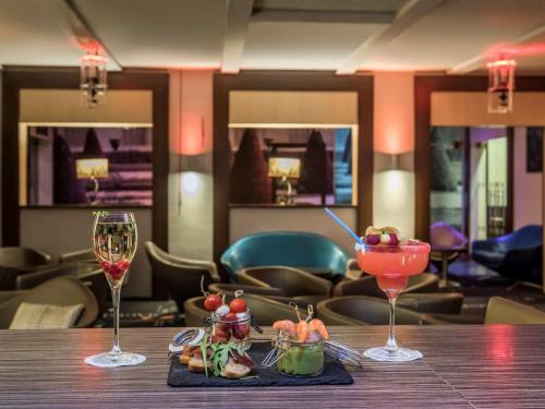 a table with two wine glasses and a tray of food at Mercure Paris Velizy in Vélizy-Villacoublay
