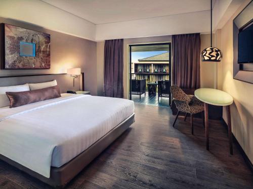 a hotel room with a bed and a dining room at Mercure Bali Legian in Legian