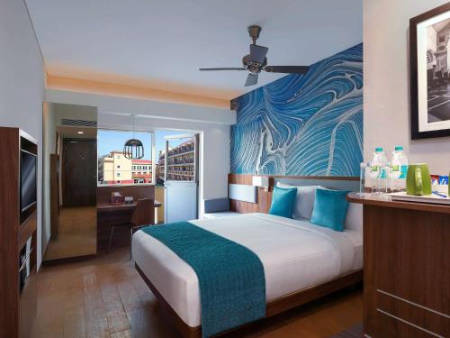 a bedroom with a large bed with a blue wall at ibis Styles Goa Calangute - An Accor Brand in Calangute