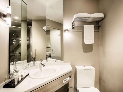 a bathroom with a sink and a toilet and a mirror at Ibis Mackay in Mackay
