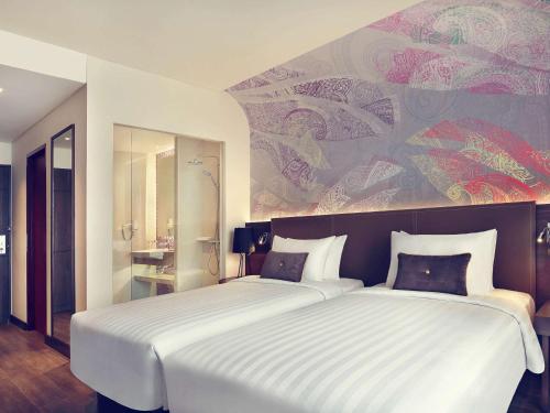 a bedroom with a large bed with a large painting on the wall at Mercure Karawang in Karawang