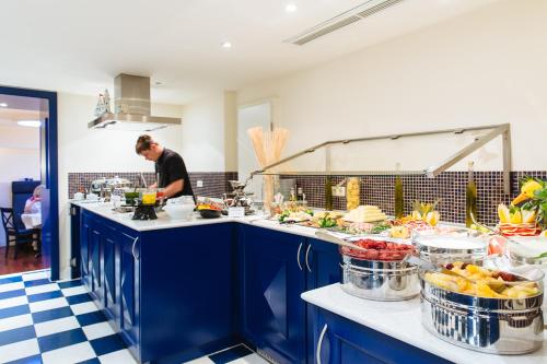 Um homem de pé numa cozinha a preparar comida. em Strandhotel Binz em Binz