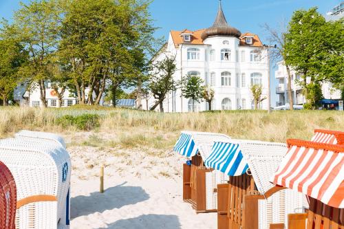 - une rangée de chaises de plage en face d'une maison dans l'établissement Strandhotel Binz, à Binz