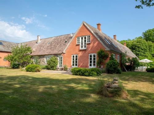 a large red brick house with a grass yard at Mellem-rummet Guesthouse & Glamping in Tanderup