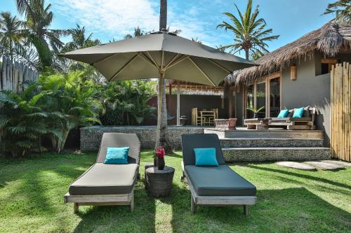 eine Terrasse mit zwei Stühlen und einem Sonnenschirm in der Unterkunft Slow - Private Pool Villas & Spa in Gili Air