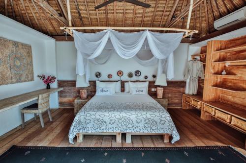 een slaapkamer met een bed en een tafel bij Slow Gili Air in Gili Air