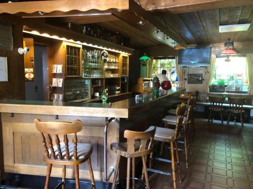 eine Bar mit Holzhockern in einem Restaurant in der Unterkunft Hotel Landhaus Köln in Lindlar
