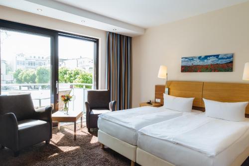 a hotel room with a bed and two chairs at Strandhotel Binz in Binz