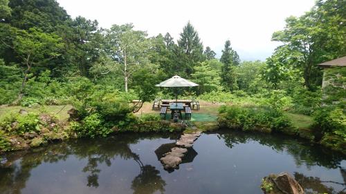 a picnic table in a garden next to a pond at Hotel Mumon in Myoko