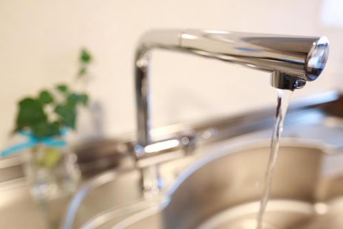 a kitchen sink with water running from a faucet at K's House Takayama Oasis [2nd K's Hostel] in Takayama