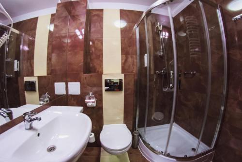 a bathroom with a shower and a toilet and a sink at Hotel Pikul in Puławy