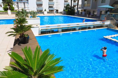 a man swimming in a large blue swimming pool at UHC Novelty Apartments in Salou