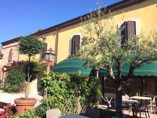a building with a tree and a table and chairs at Hotel Antichi Cortili in Dossobuono