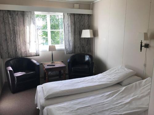 a hotel room with a bed and two chairs and a table at Rørosvidda Hotell in Røros