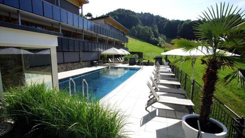 a hotel with a swimming pool with chairs and a palm tree at St Hubertus BnB in Egg