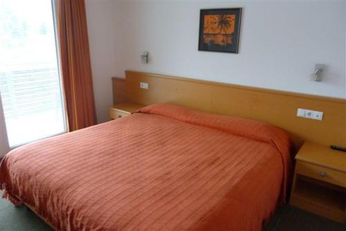 a bedroom with a orange bed and a window at Garni Cremona in Bressanone