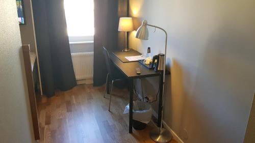 a room with a desk with a lamp and a phone at City Hotel in Kristinehamn