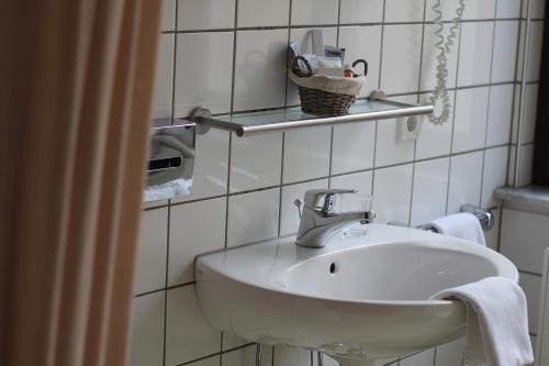 a white sink in a white tiled bathroom at Hotel Centro in Stuttgart