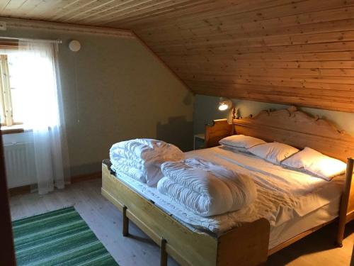 sypialnia z dużym łóżkiem i drewnianym sufitem w obiekcie Högetorp w mieście Oskarshamn