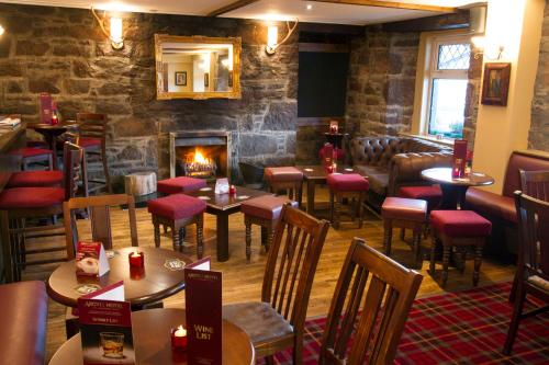 a restaurant with tables and chairs and a fireplace at Argyll Hotel in Ullapool