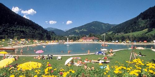a group of people laying in the grass near a lake at Landhotel Berger in Eben im Pongau