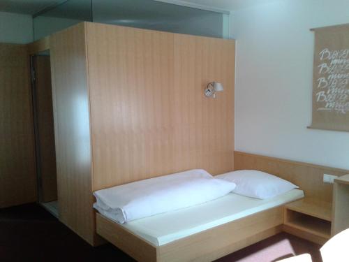 a bed with white sheets and a wooden wall at Haus der Begegnung in Innsbruck