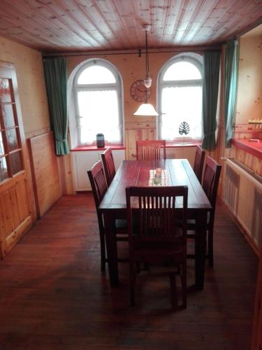 una sala da pranzo con tavolo e sedie e due finestre di Ferienzimmer Saatmann ad Amorbach