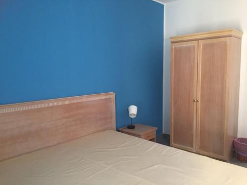 a blue bedroom with a bed and a wooden cabinet at Affacciati sulle Eolie Appartamenti sul Lungomare Patti Marina in Patti