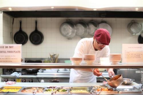 a man standing in a kitchen preparing food at Hotel New Yokosuka in Yokosuka
