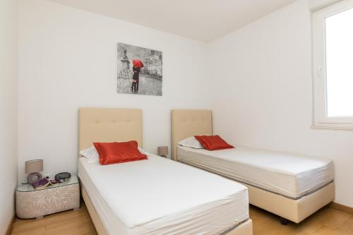 two beds in a room with white walls at Apartment Marcela With Private Parking in Split
