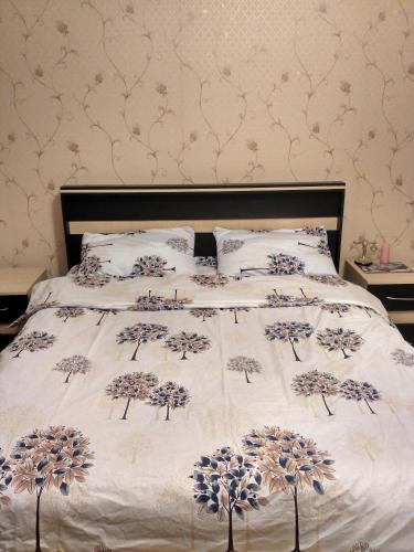 a bed with a white bedspread with blue flowers on it at Sweet home Gusar. in Qusar