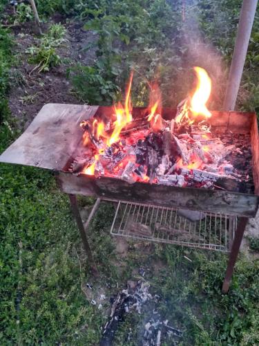 a barbecue grill with fire in the grass at Sweet home Gusar. in Qusar